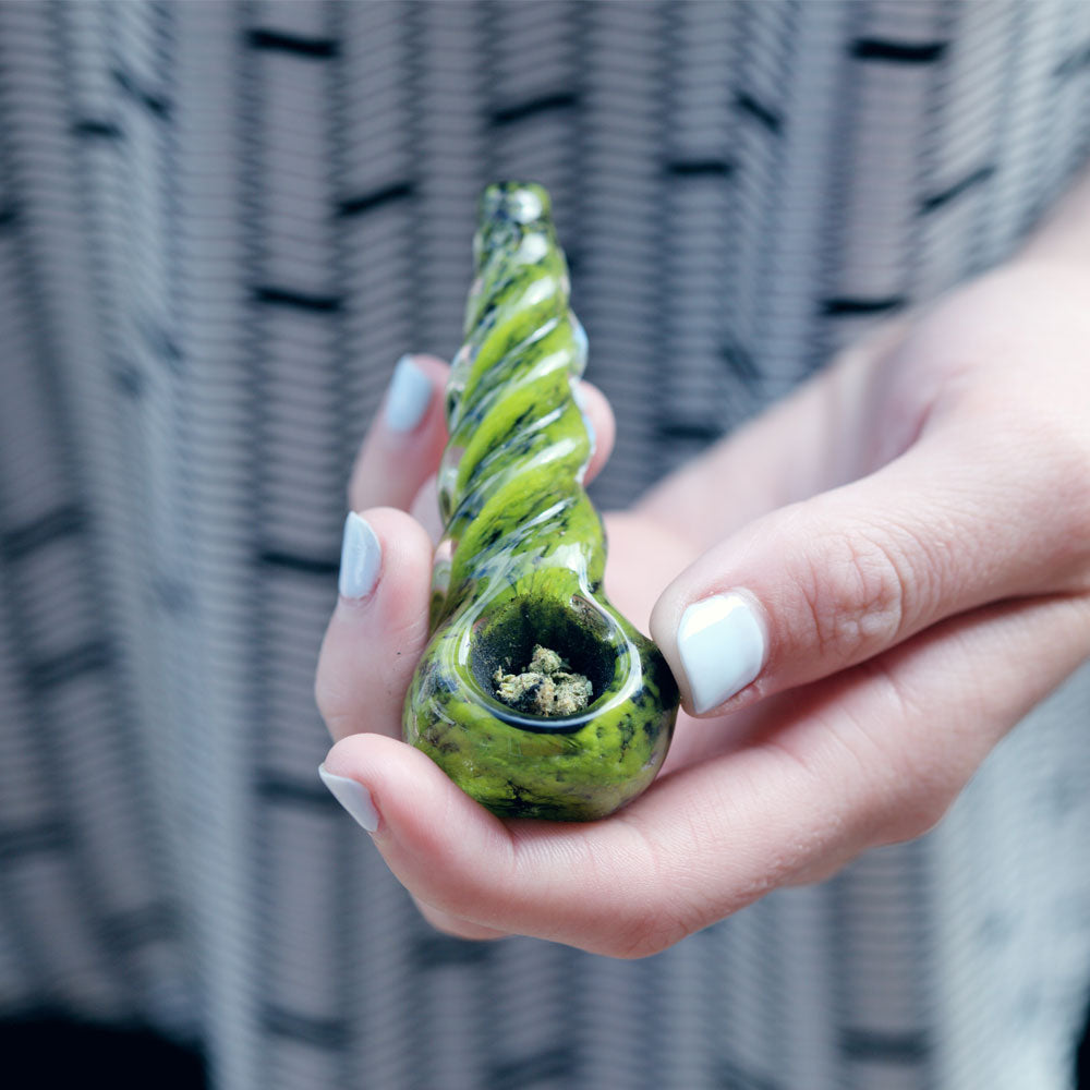 Woman hold out pipe with dry herbs inside