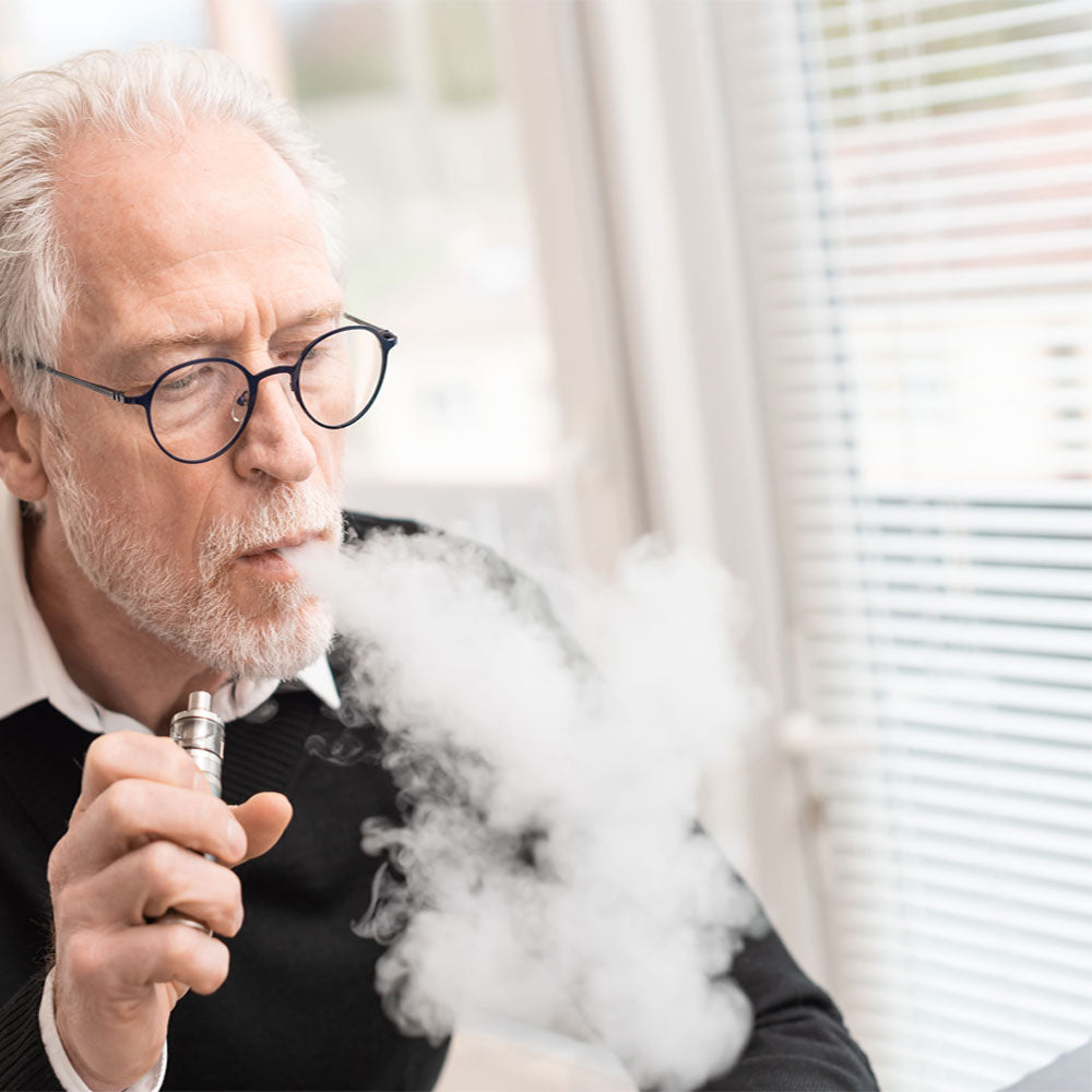 Old man vaping and blowing out smoke