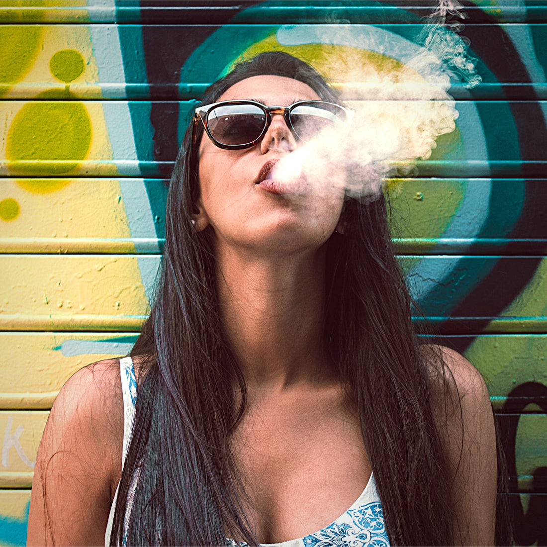 Girl with long hair in sunglasses blowing vapors