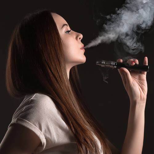 Woman vaping and blowing out smoke