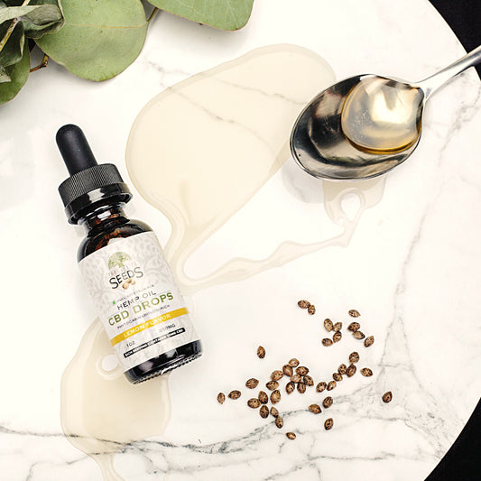 Hemp oil cbd drops tincture on table with spoon and hemp seeds