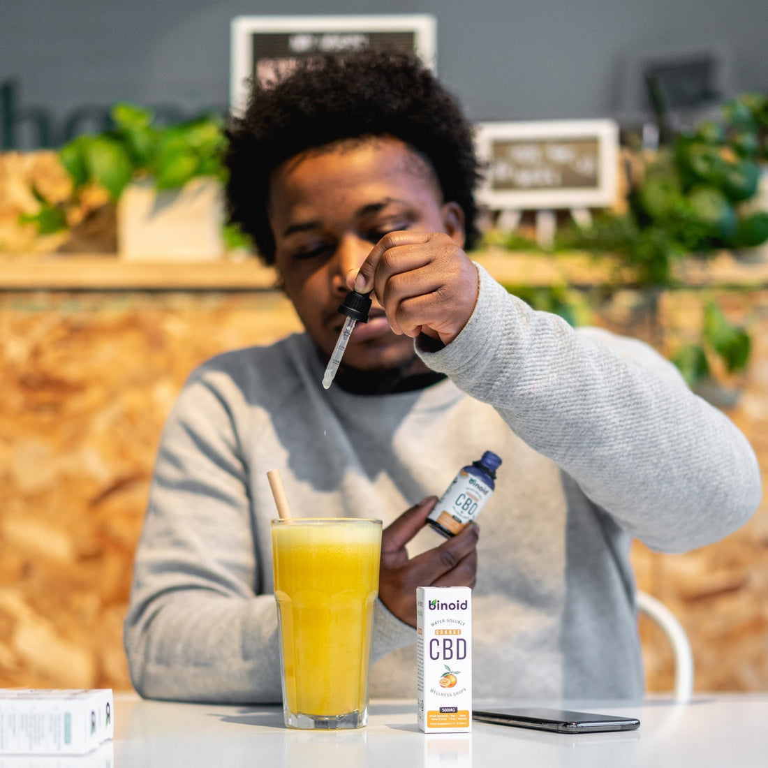 Man dripping cbd drops into orange juice at restaurant