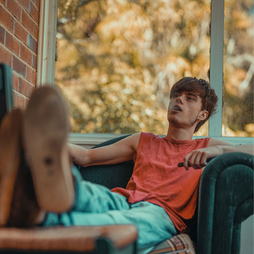 Young Man Sitting in a Sofa Chair While Vaping