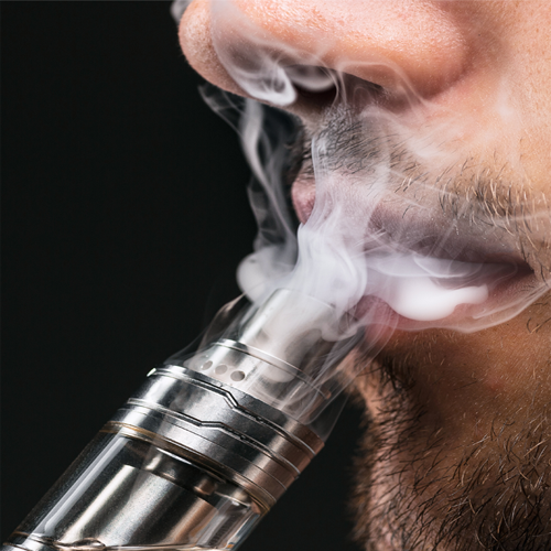 Man vaping and blowing smoke