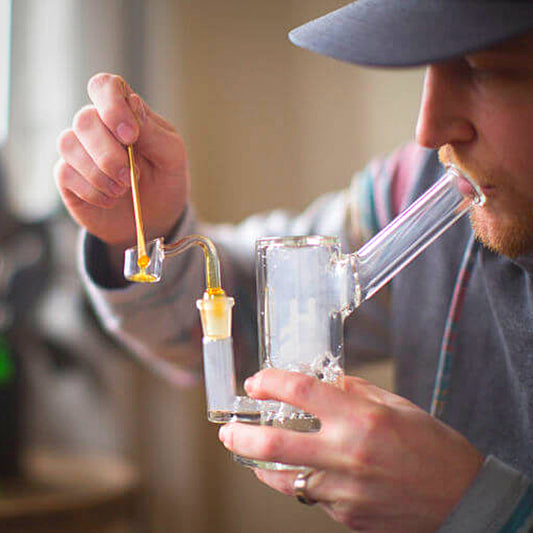 Man dabbing wax with glass dab rig and dab nail